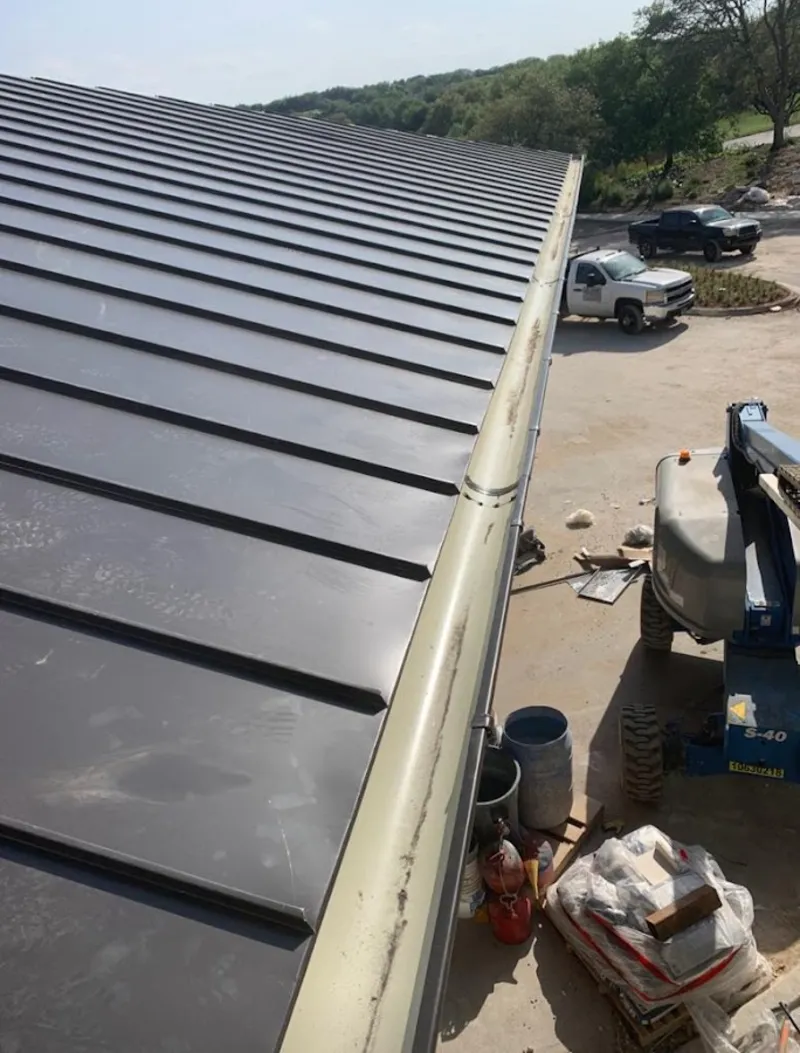 Standing seam panel and gutter detail on a metal roofing jobsite in Elgin
